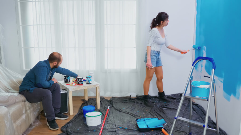 wife painting wall with roller brush